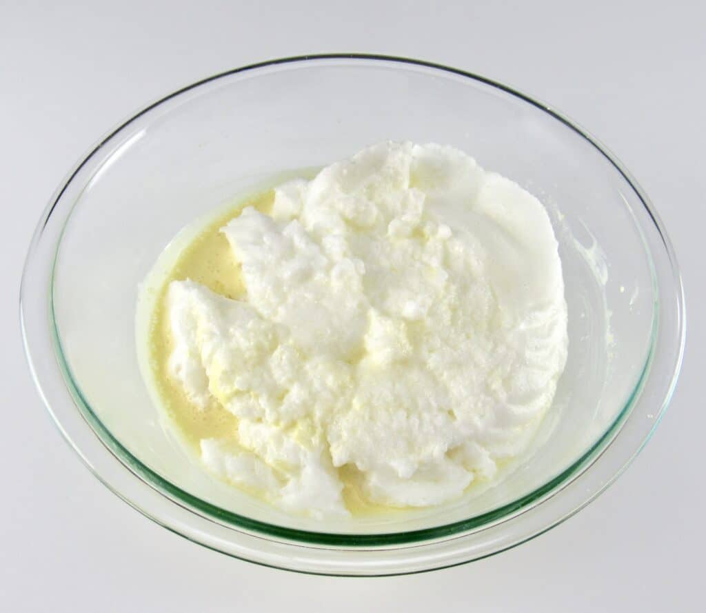 egg whites on top of wet ingredients for cake in glass bowl