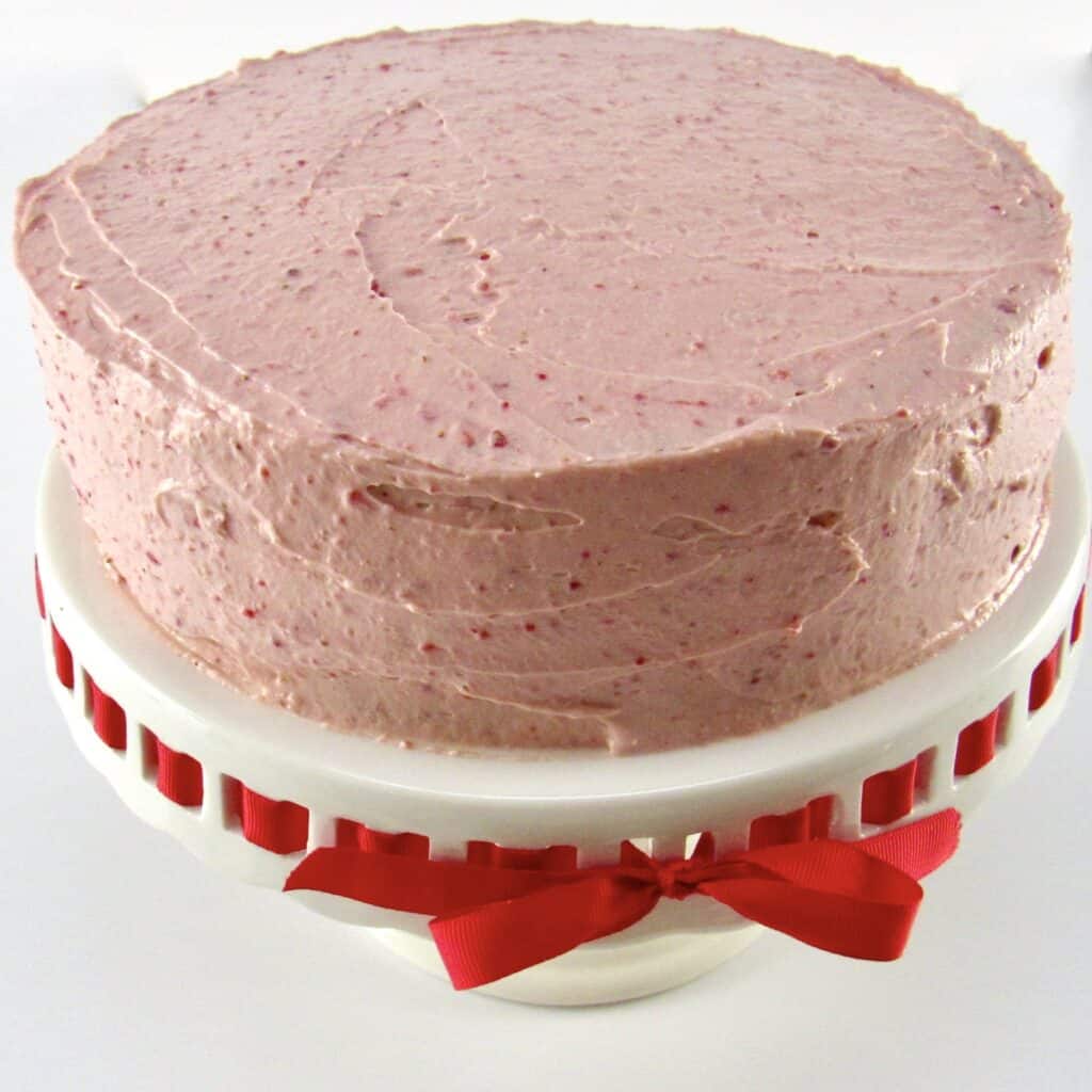 strawberry frosted cake on cake stand