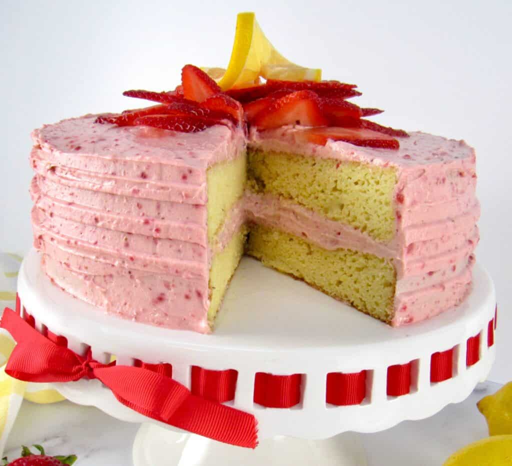 strawberry cake on cake stand with strawberries on top with slice missing