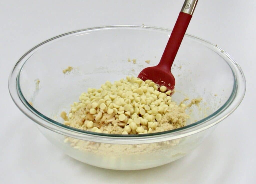 cookie dough with white chocolate chips in bowl with red spatual