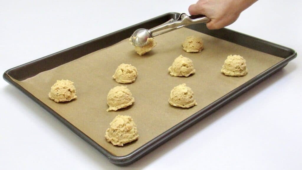 cookie dough being scooped onto baking sheet