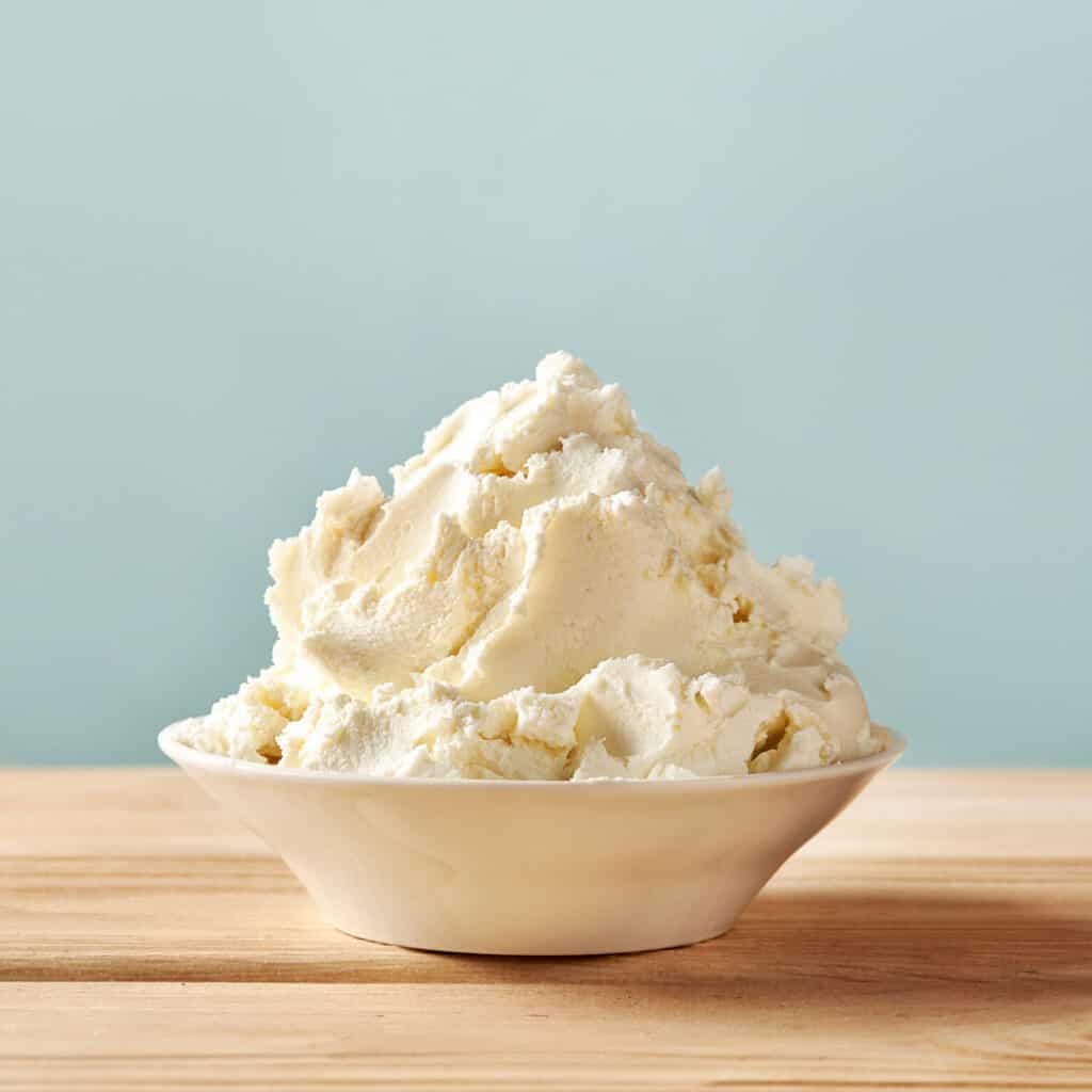 Mascarpone Cheese piled up in a white bowl on a cutting board