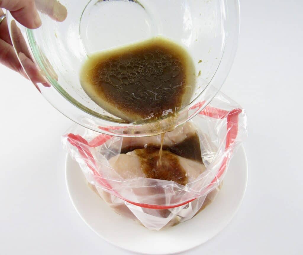 dressing being poured over chicken in baggie