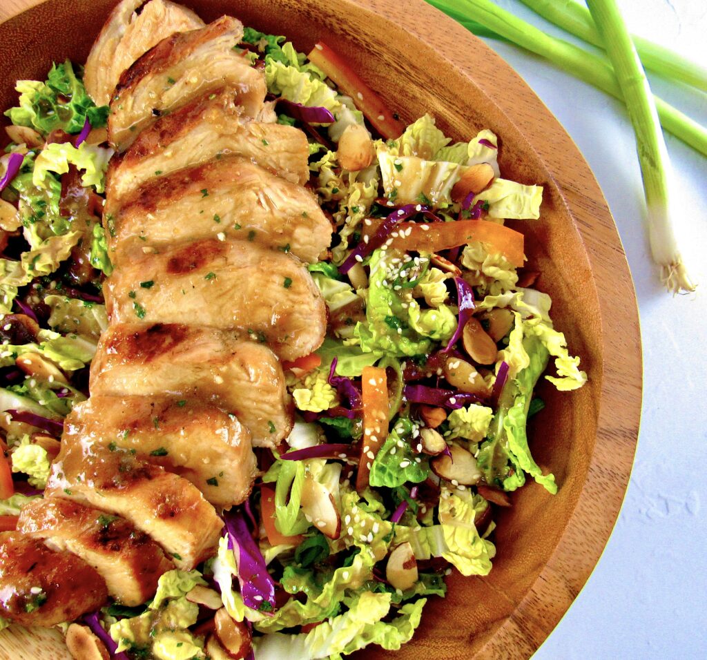 overhead view of sliced grilled chicken on asian salad