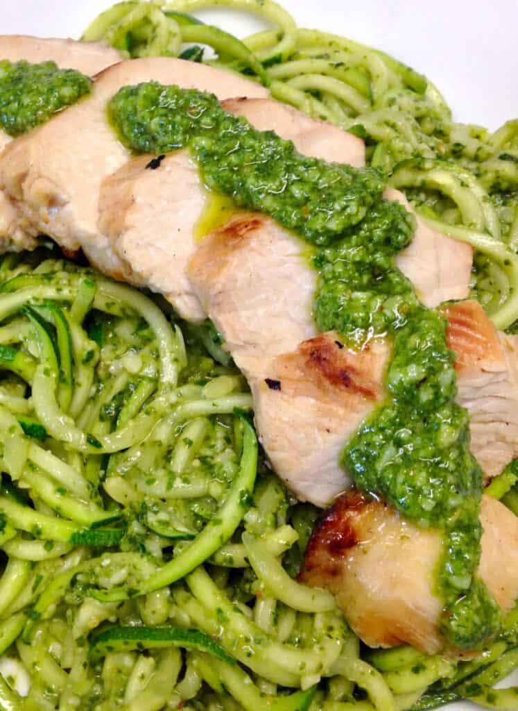 zucchini noodles with pesto sauce and sliced grilled chicken over the top
