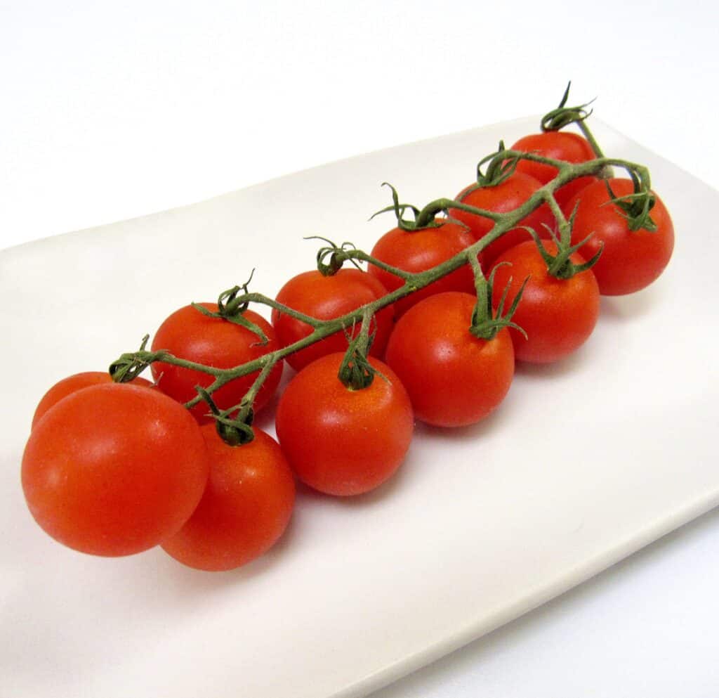 vine of cherry tomatoes on white plate