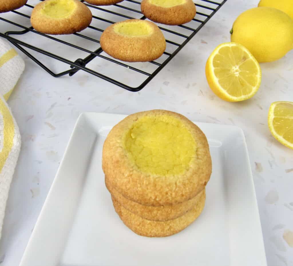 lemon curd thumbprint cookies stacked on white plate