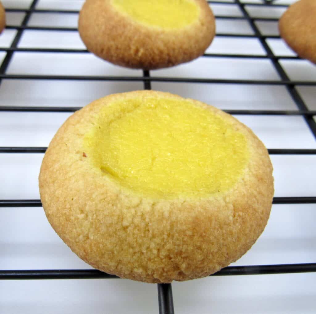 closeup of lemon curd thumbprint cookie on cooling rack