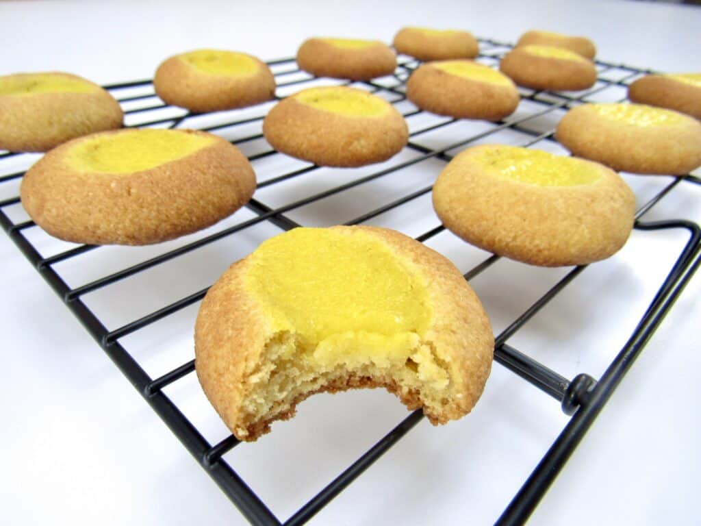baked thumbprint cookies on cooling rack with bite taken out of one