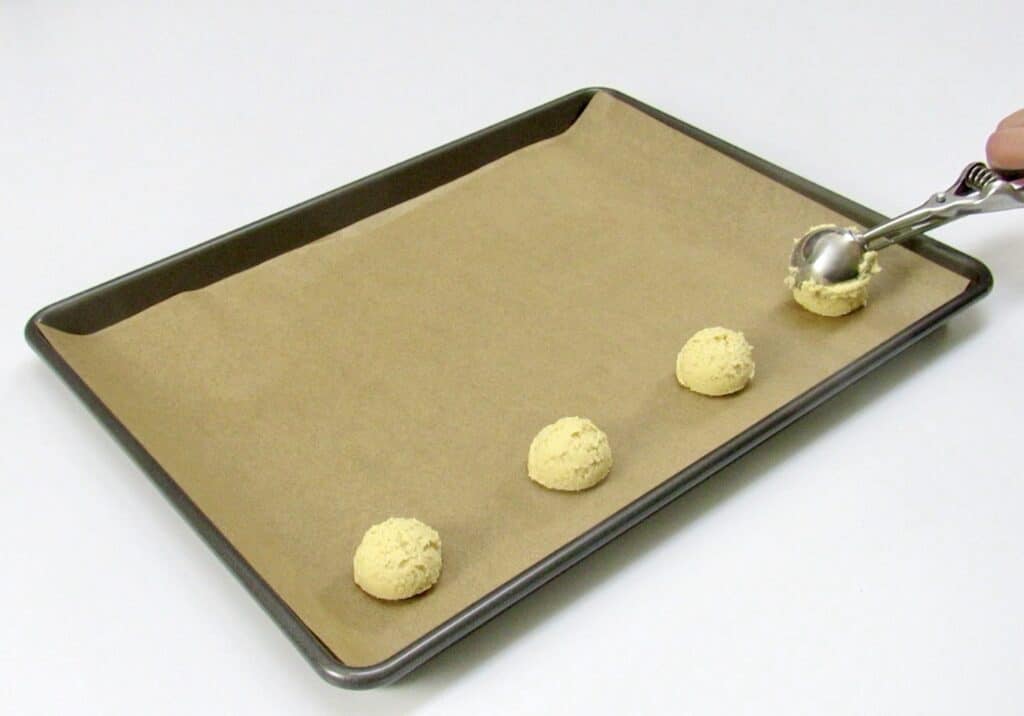 thumbprint cookies being scooped onto baking sheet