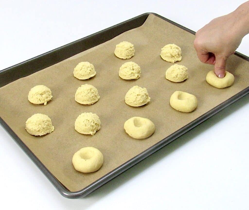 thumbprint cookie dough on baking rack with thumb in one