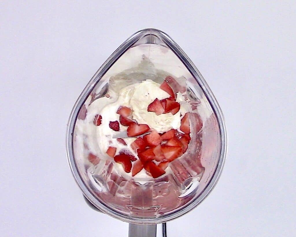 ingredients for strawberry smoothie in bowl of blender