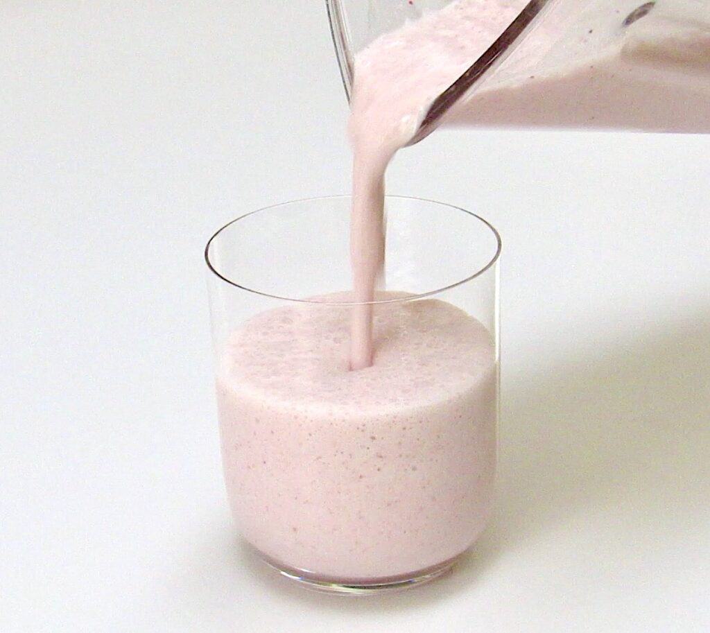 strawberry smoothie being poured into glass