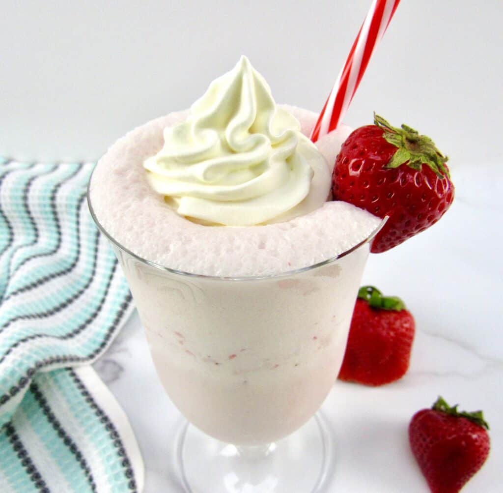 overhead of view of strawberry smoothie with whip cream and strawberry on glass