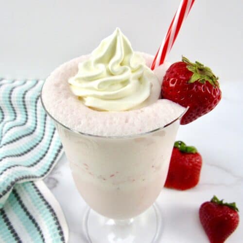 overhead of view of strawberry smoothie with whip cream and strawberry on glass