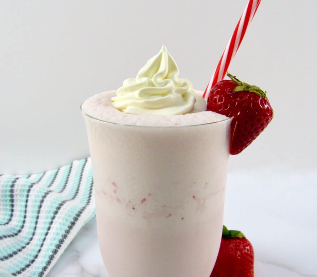 strawberry smoothie with whip cream and strawberry on glass