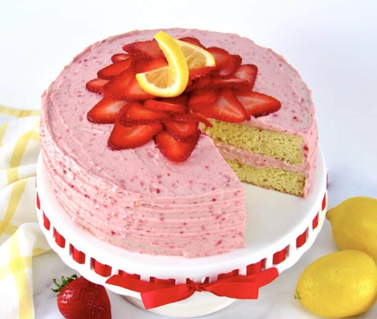 strawberry cake on cake stand with strawberries on top with slice missing