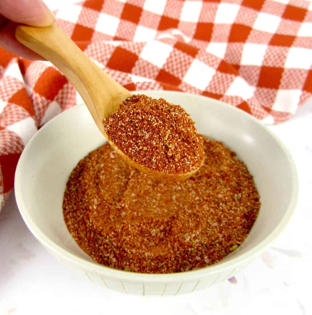 blackened seasoning mix in bowl with wooden spoon holding up some