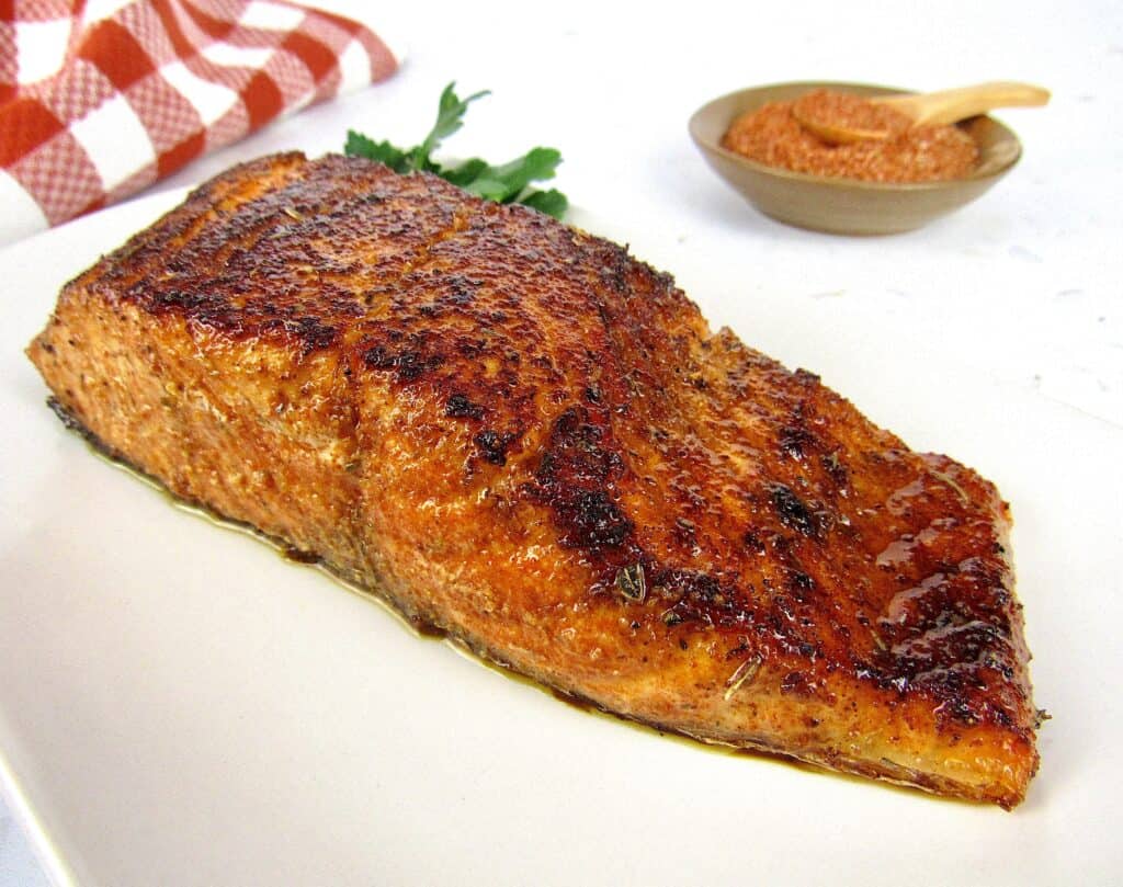 blackened salmon on a plate with spices in the background