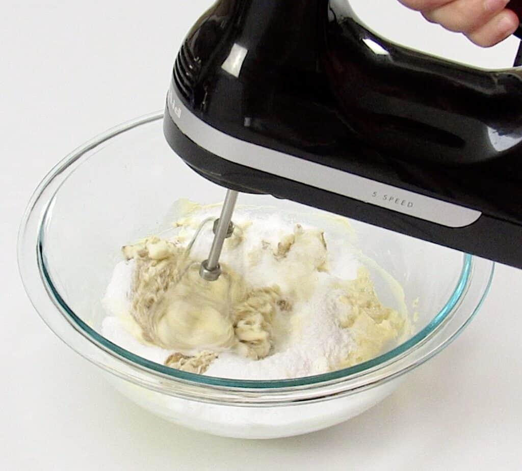 vanilla frosting ingredients in glass bowl being mixed