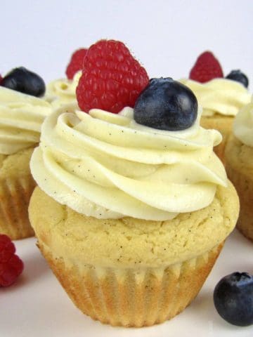 closeup of vanilla cupcake with raspberry and blueberry on top