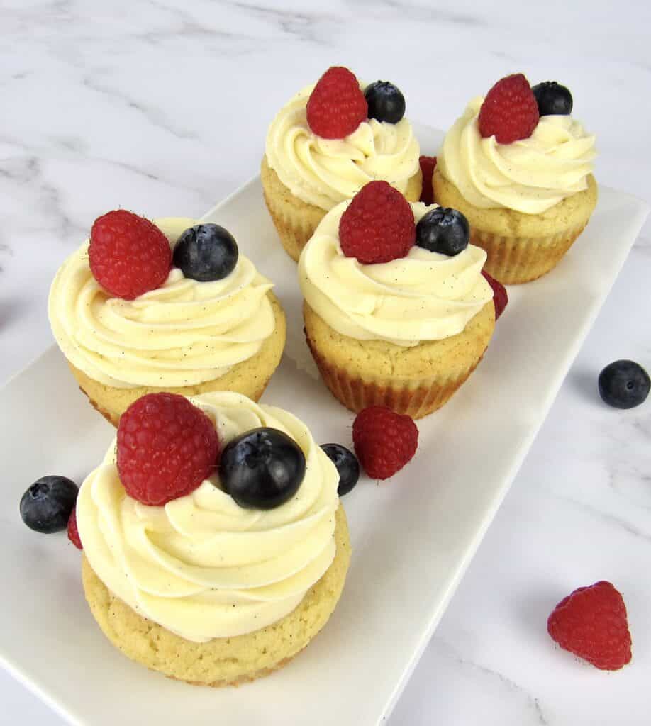 overhead view of vanilla cupcake with raspberry and blueberry on top