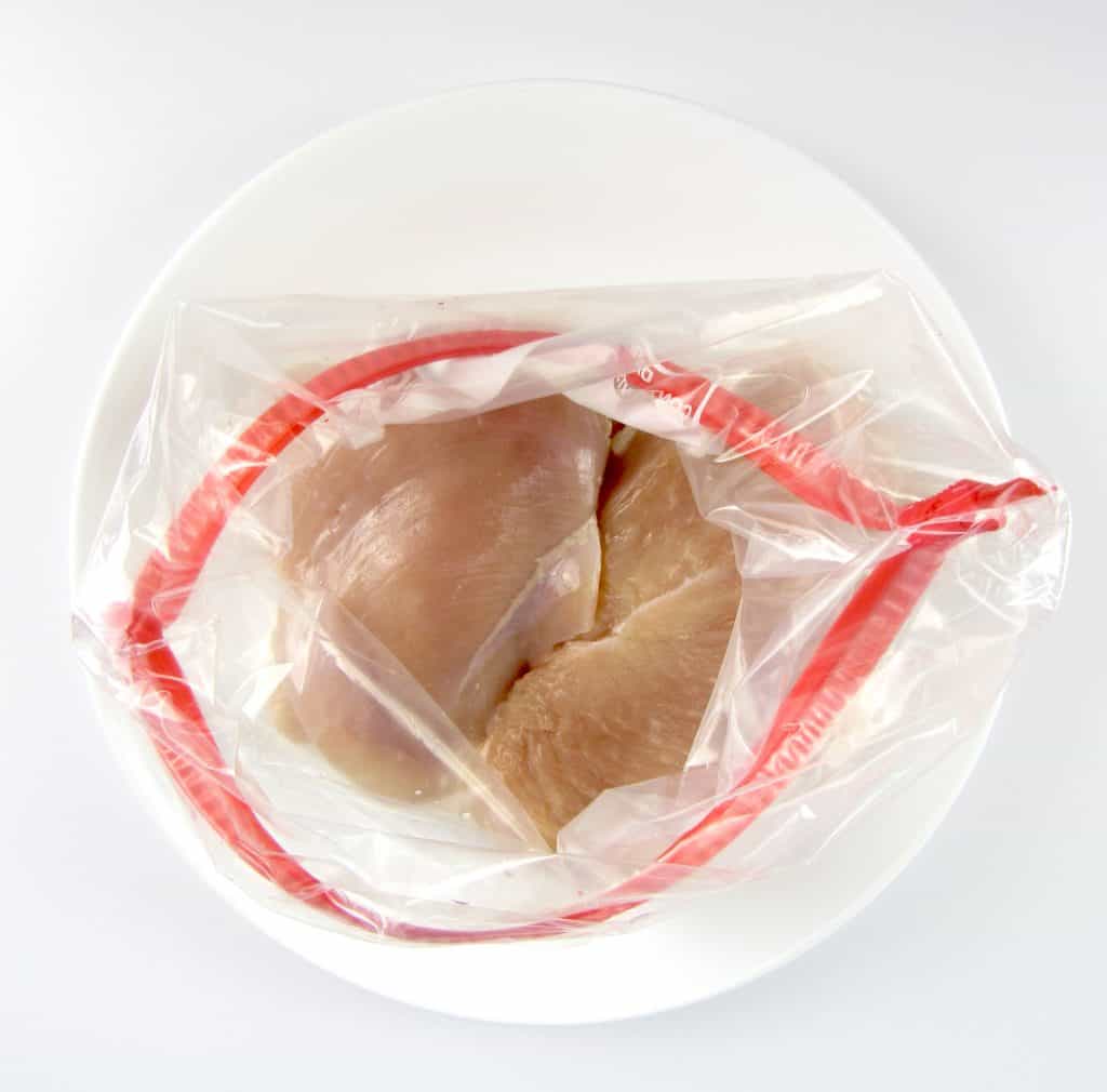 open food storage bag with chicken breasts in it