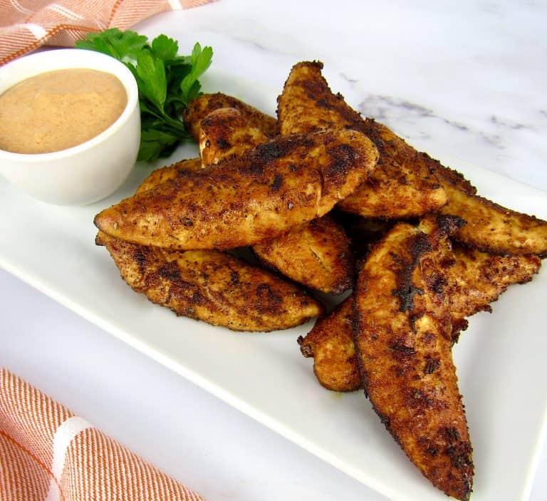 overhead view of blackened chicken tenders on white plate with dipping sauce on side