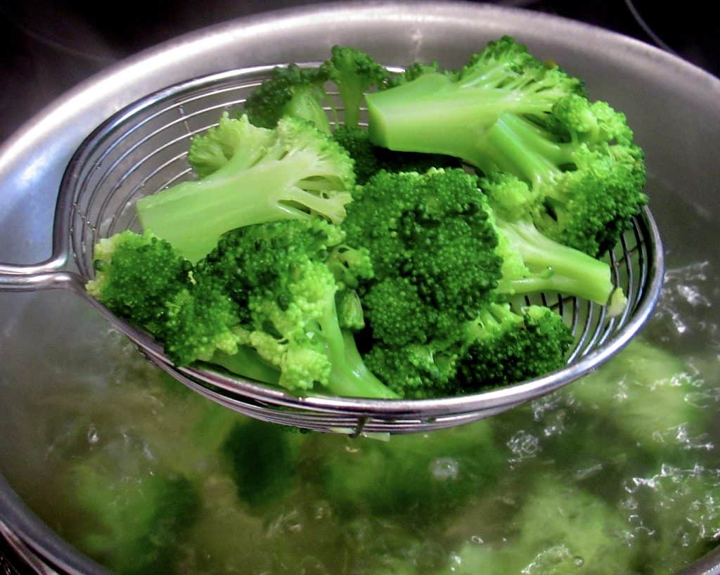 boiled broccoli being held up with spider