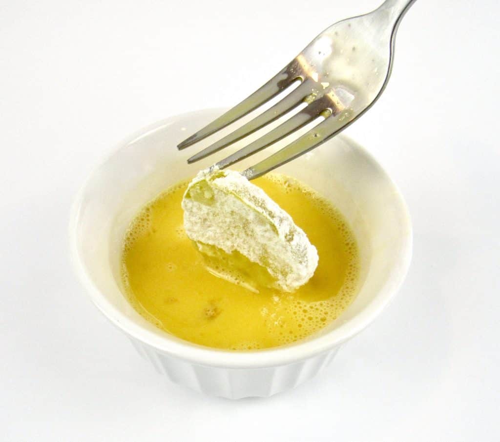 pickle slice being dipped in egg with fork