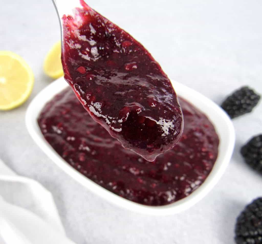 blackberry jam in spoon being held up
