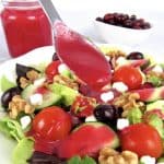 cranberry dressing in spoon held over salad