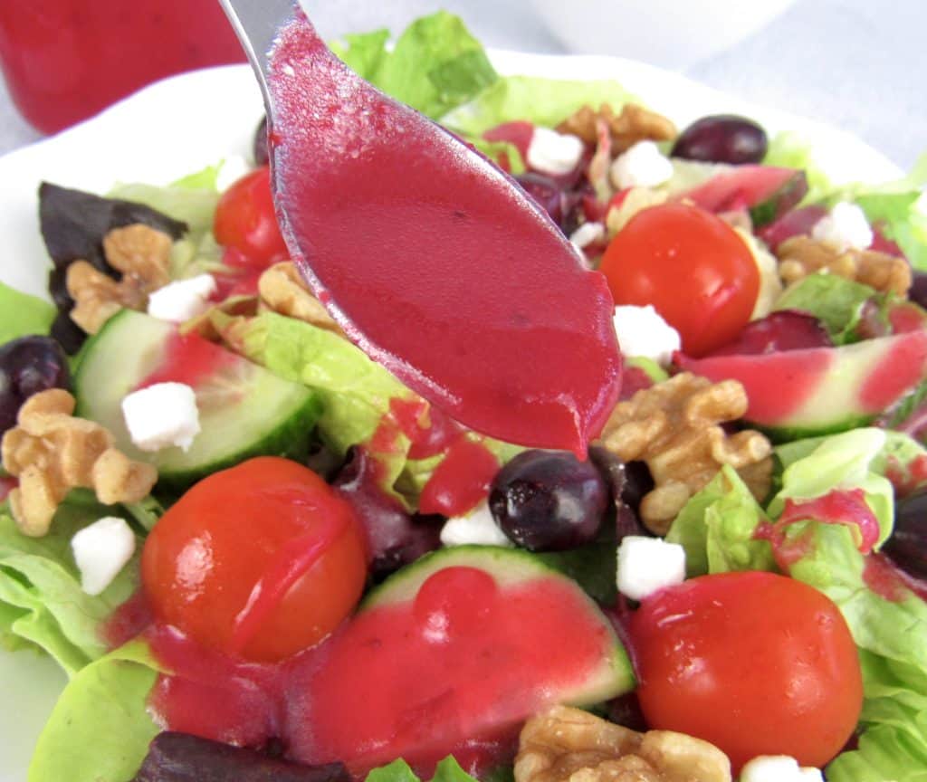 cranberry dressing in spoon held over salad