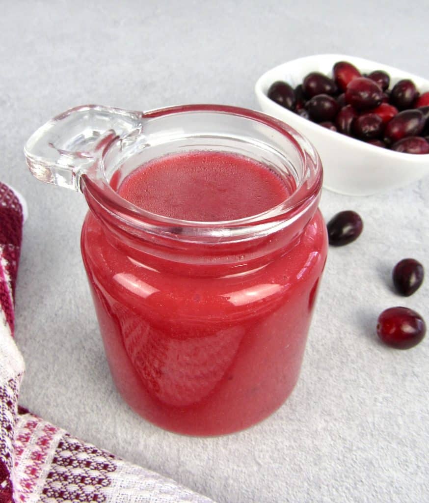 cranberry dressing in glass jar with cranberries in background