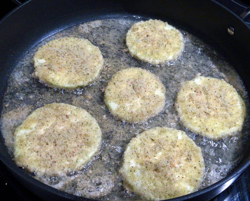 slices of breaded eggplant frying in skillet