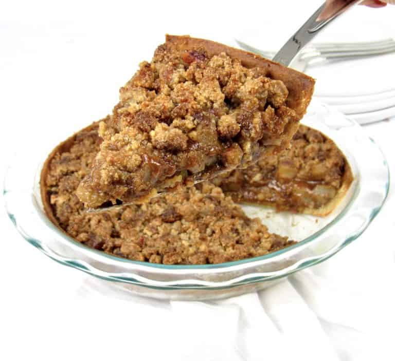 slice of dutch apple pie being held up over pie