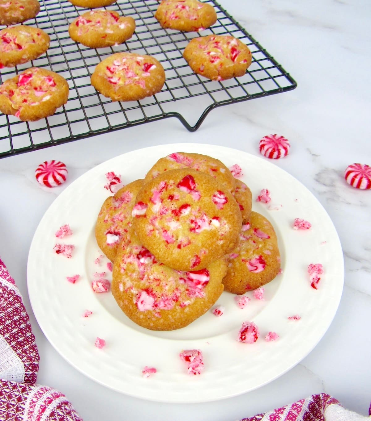 Keto White Chocolate Peppermint Cookies on white plate with more on cooling rack in back