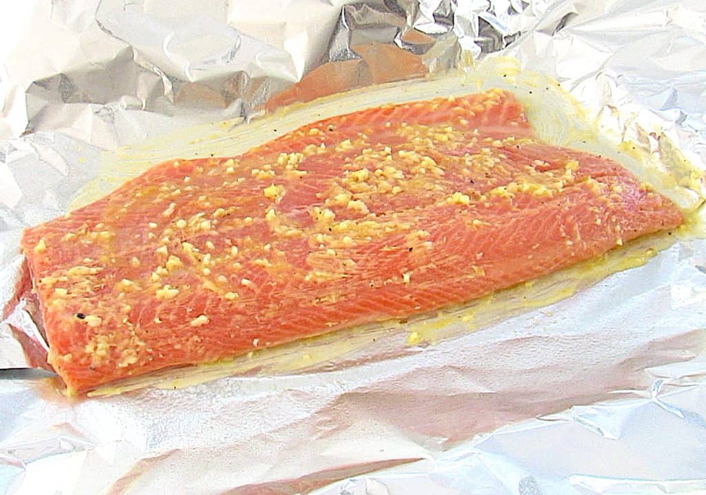salmon on foil with garlic butter on top