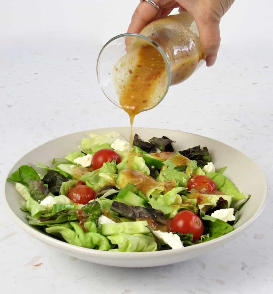 Vinaigrette being poured over salad