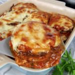 eggplant parmesan being spooned out of a casserole