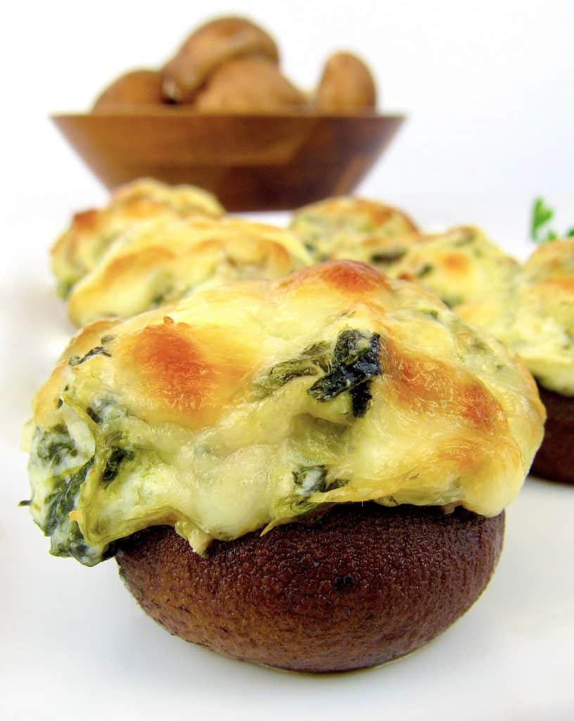 Spinach Artichoke Stuffed Mushrooms with mushrooms in background