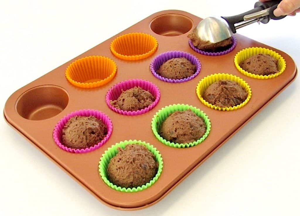 chocolate muffins batter being spooned into muffin pan