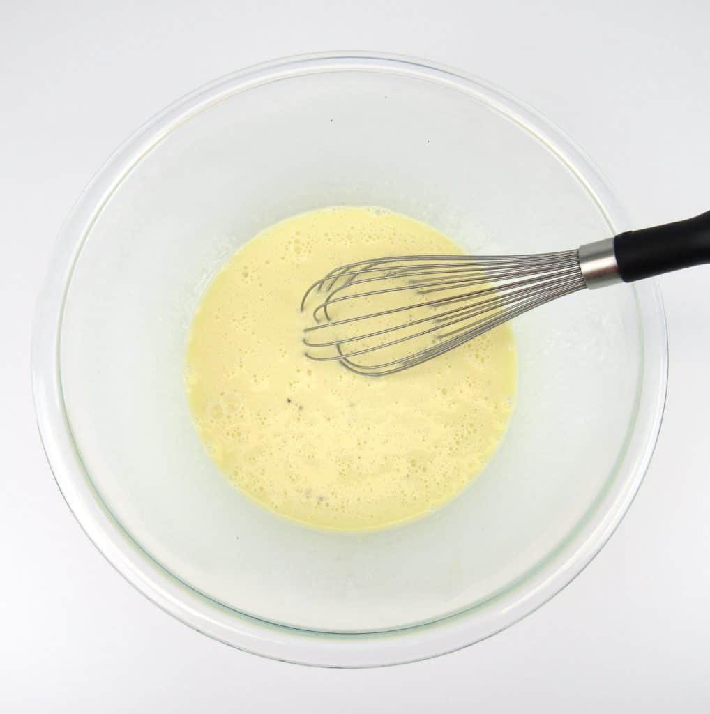 eggs and cream beaten together in glass bowl with whisk