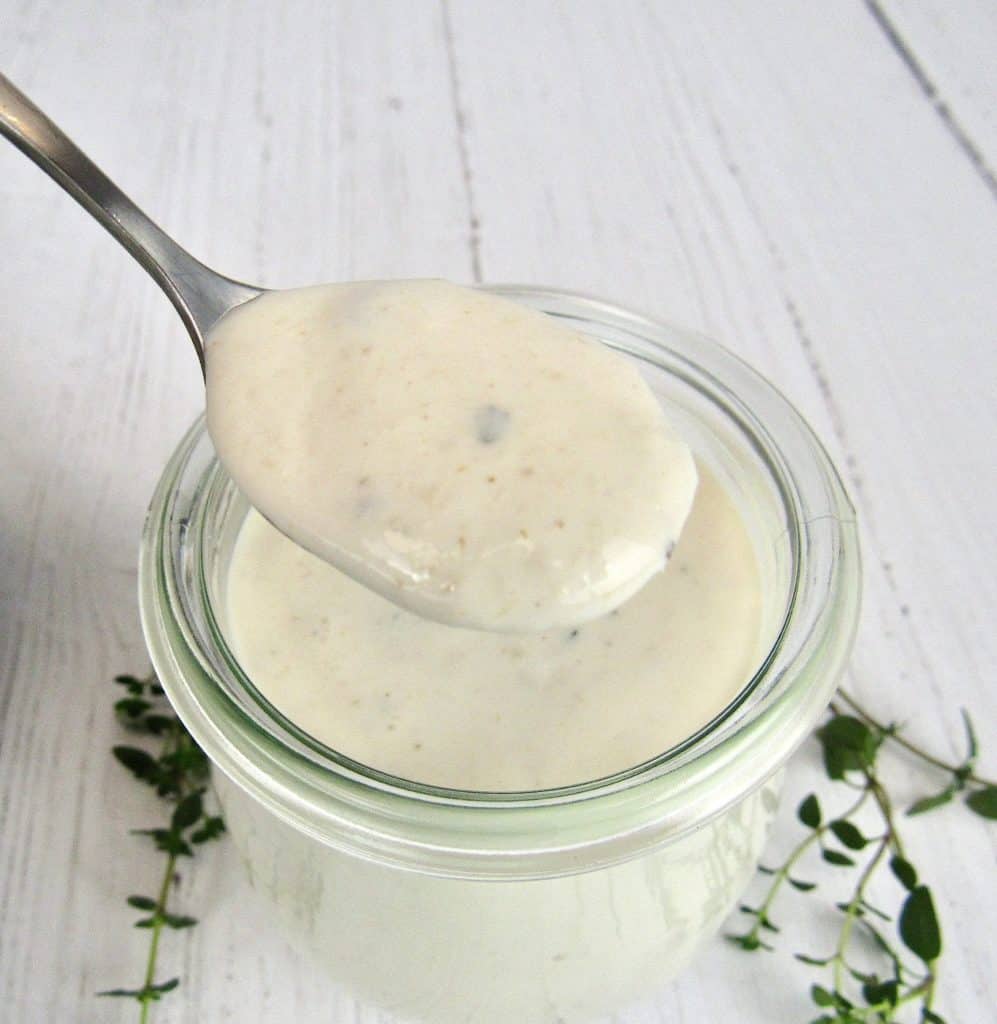 Creamy Horseradish Sauce in glass jar with spoon holding up some