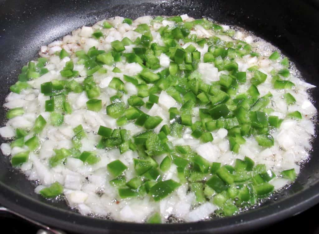 jalapeno peppers and onions frying in skillet