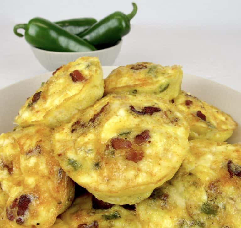 Jalapeno Popper Egg Cups piled up in bowl with jalapenos in background