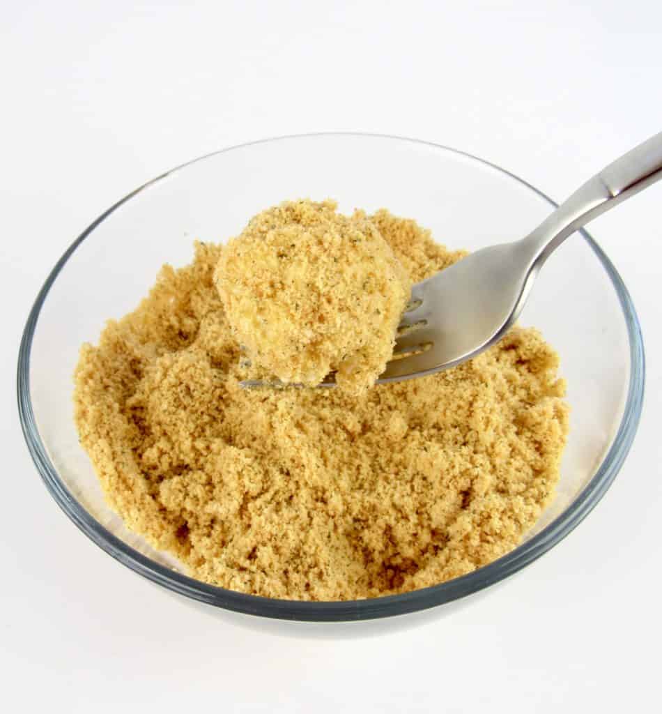 cauliflower being dipped into bread crumbs