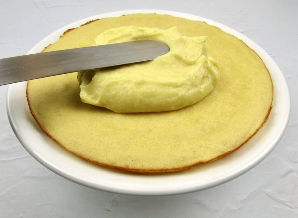 lemon cake with frosting being spread on top