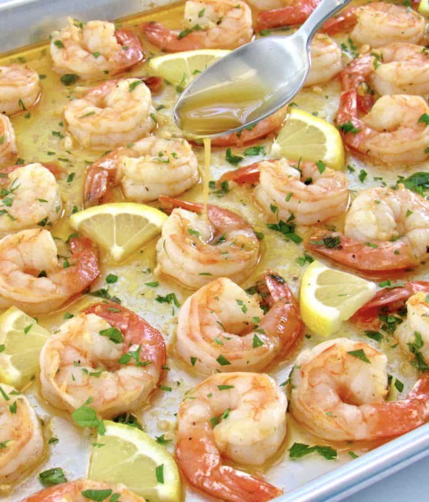 garlic butter shrimp on baking sheet with butter spooned on top