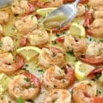 garlic butter shrimp on baking sheet with butter spooned on top